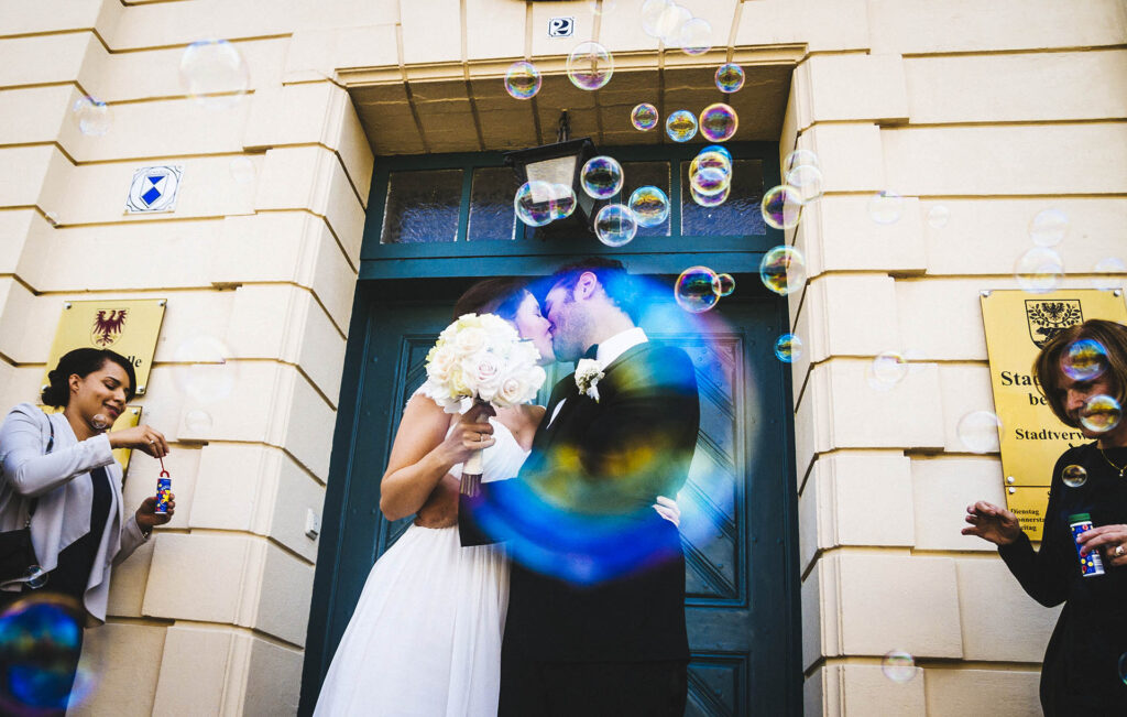 Wedding Photographer - newlyweds kissing through soap bubble