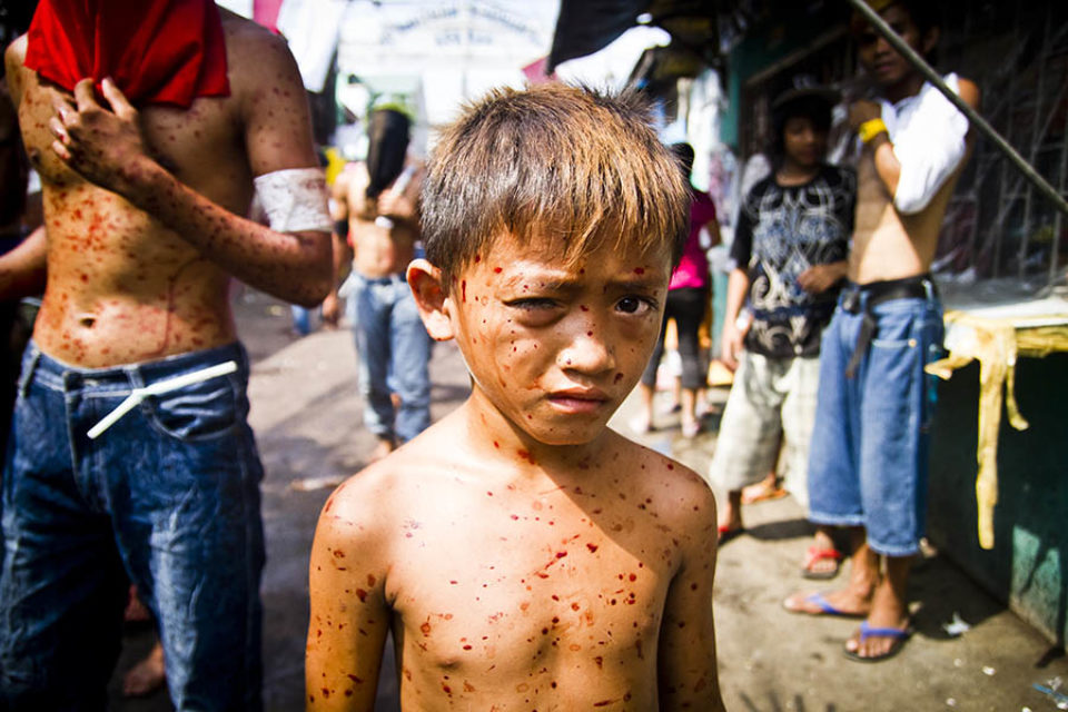 Blood spattered young boy watching processions