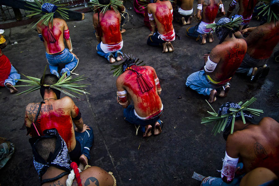 Blood-covered celebrants pray in street