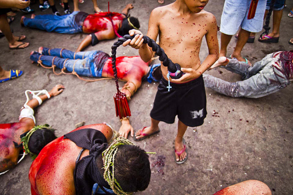 Boy holding praying celebrant's whip