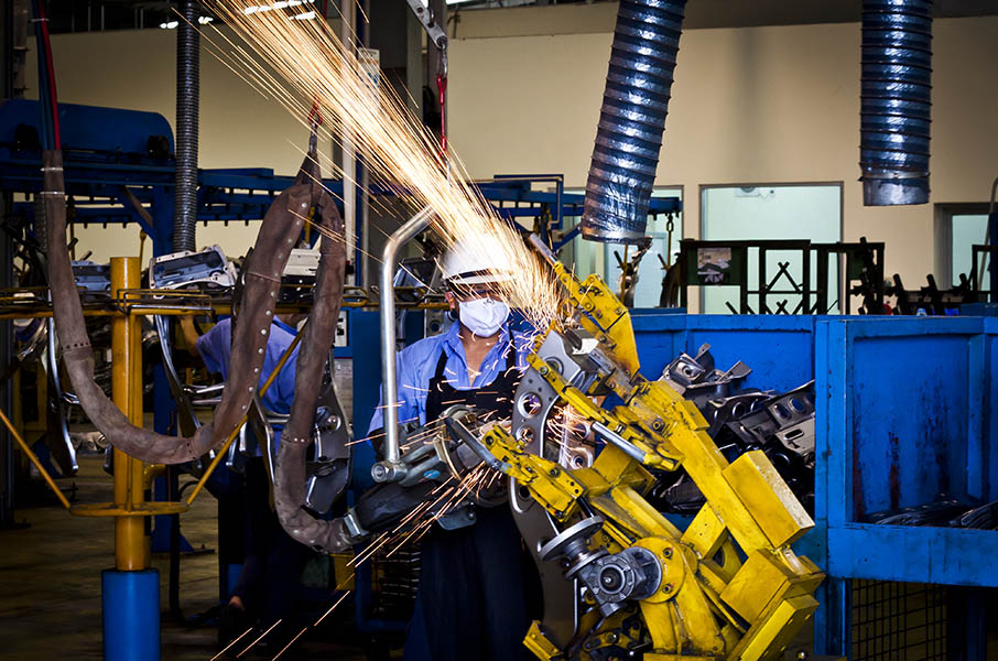 A factory worker welds a scooter chassis in the Piaggio factory in Vietnam