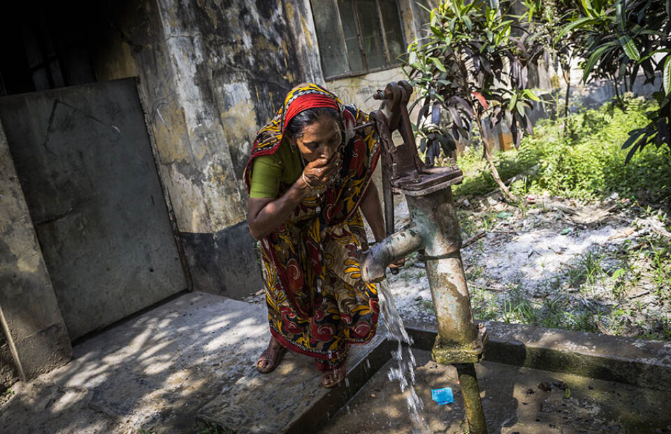 A woman drinking from a rural tubewell